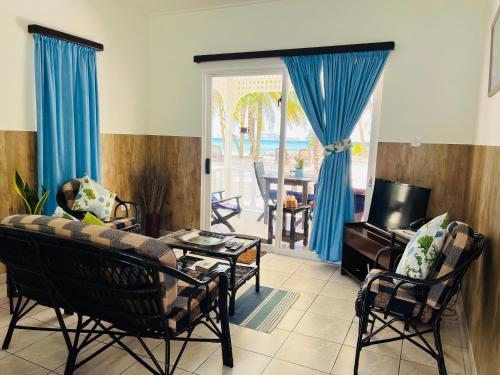 ein Wohnzimmer mit einem Sofa, Stühlen und einem Tisch in der Unterkunft Cap Jean Marie Beach Villas in Anse Kerlan