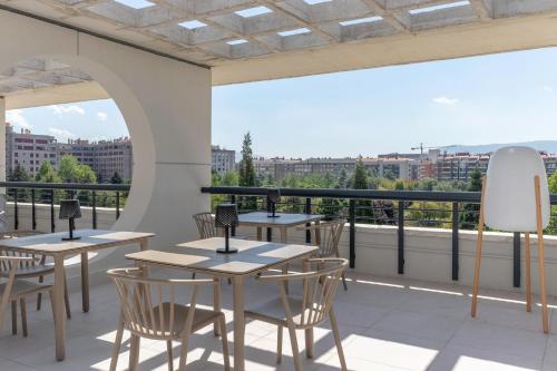 a patio with tables and chairs on a balcony at Apartamentos Líbere Pamplona Yamaguchi in Pamplona
