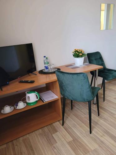 ein Wohnzimmer mit einem Tisch, einem TV und Stühlen in der Unterkunft Viešbutis RASA in Raseiniai