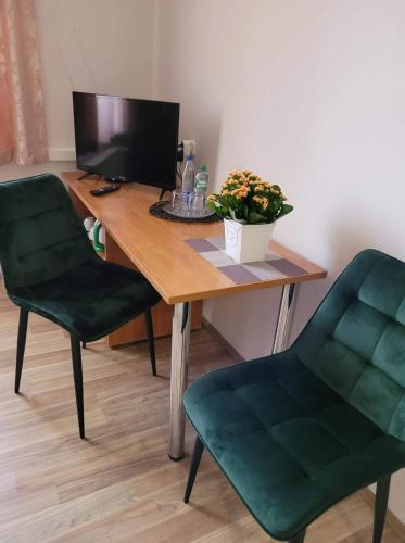 a desk with a computer and two green chairs at Viešbutis RASA in Raseiniai