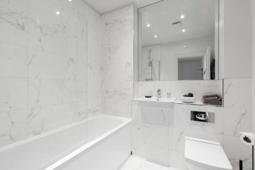 uma casa de banho branca com uma banheira e um lavatório em Elliot Oliver - Cosy 2 Bedroom Town Centre Apartment em Cheltenham
