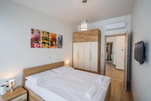 1 dormitorio con 1 cama blanca y TV en Silver Lodge Siófok en Siófok