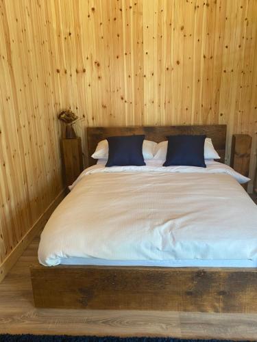 a bed in a room with a wooden wall at Kingfisher Cabin - Wild Escapes Wrenbury off grid glamping - ages 12 and over in Baddiley