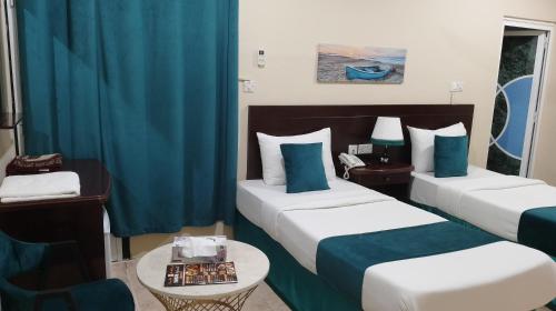 um quarto de hotel com duas camas e uma mesa em Sadaf Hotel Apartments em Soar