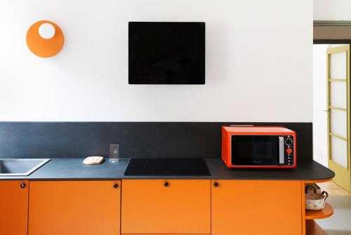 een oranje magnetron bovenop een aanrecht bij Smart 1-bed with modern amenities in Milaan