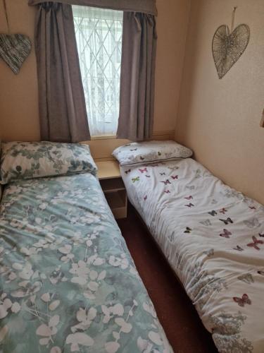 two beds sitting in a room with a window at Corner pitch 4 berth caravan in Ingoldmells