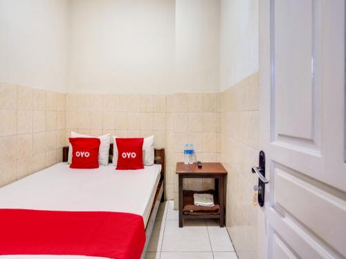 Habitación pequeña con 2 almohadas rojas en una cama en OYO Life 91511 Ampel Residence Syariah, en Surabaya