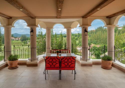 Toscana Valley Castello Della Vella في مو سي: شرفة مع كراسي حمراء وطاولة مطلة