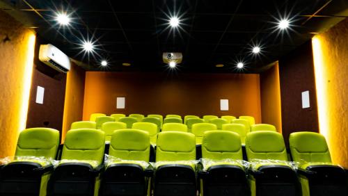 an empty auditorium with green chairs in a theater at The Village Resort Mundra in Mundra