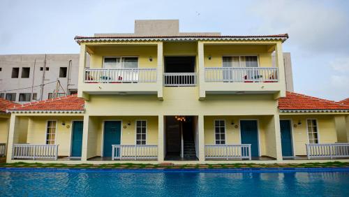 a yellow house with blue doors and a swimming pool at The Village Resort Mundra in Mundra