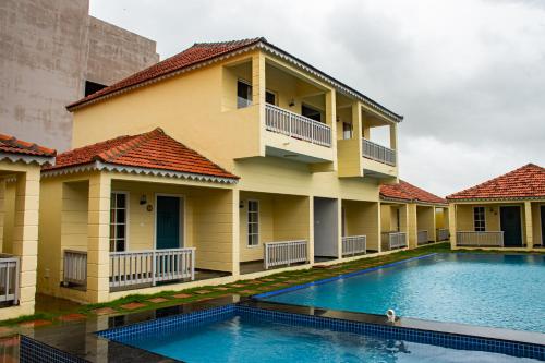a house with a swimming pool in front of it at The Village Resort Mundra in Mundra