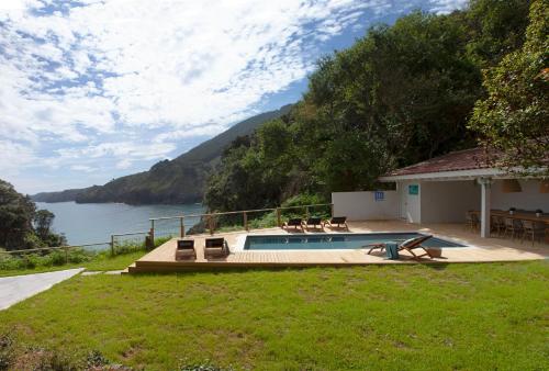 een huis met een zwembad naast een waterlichaam bij Exclusiva Villa con piscina al borde del mar con vistas de película in Pechón