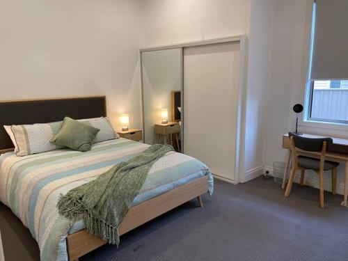 a bedroom with a bed and a desk and a mirror at Walnut House - Hargreaves St close to Lake Weeroona in Bendigo