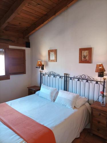 a bedroom with a large bed with white sheets at La Casa de los Gatos in Condemios de Abajo