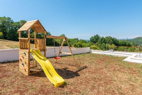 a playground with a slide and a house at Villa Emi in Karojba