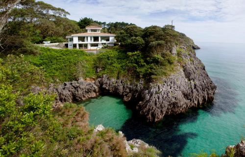 een huis op een klif boven de oceaan bij Exclusiva Villa con piscina al borde del mar con vistas de película in Pechón