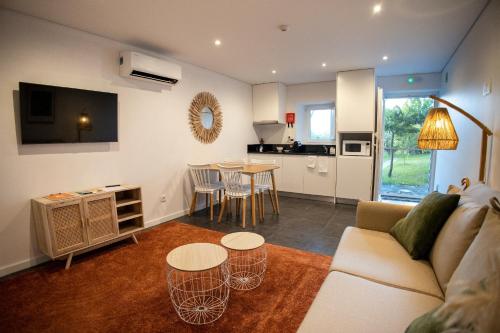 a living room with a couch and tables and a kitchen at Moinho das Feteiras in Feteiras