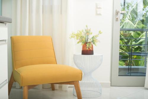 a yellow chair in a room with a window at Spectacular apartment near Dance Hall/Center in Kalamata