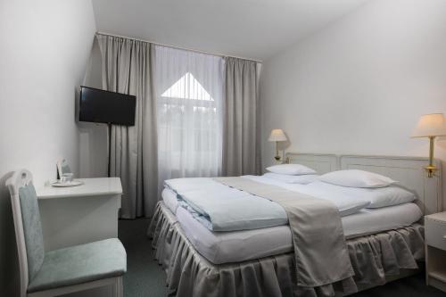una habitación de hotel con 2 camas y una silla en Hotel Ferdinand, en Mariánské Lázně