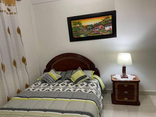 a bedroom with a bed and a table with a lamp at Apartamento amoblado a 10 minutos del centro in Bogotá