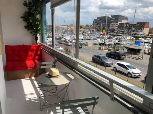 un balcón con vistas a un puerto con coches en soleil et bateau en Courseulles-sur-Mer