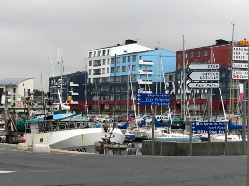 eine Gruppe von Booten, die in einem Yachthafen mit Schildern angedockt sind in der Unterkunft soleil et bateau in Courseulles-sur-Mer