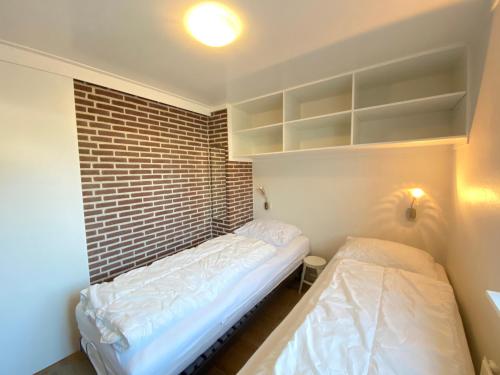 a small room with two beds and a brick wall at Op 't Landtweg 35a in Callantsoog