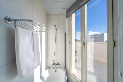 La salle de bains est pourvue d'une douche et d'une serviette blanche. dans l'établissement Quatro Puerta del Sol, à Madrid