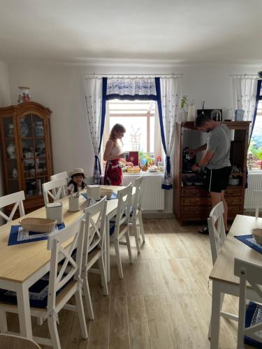 a man and woman in a kitchen with a child sitting at a table at Ubytování U Synagogy Dobříš in Dobříš