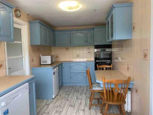 une cuisine avec des armoires bleues, une table et des chaises dans l'établissement Mountain House Omeath near Carlingford, à Ó Méith