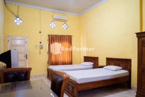 - une chambre avec 2 lits, une table et une télévision dans l'établissement Wisma Citra Metro Mitra RedDoorz, à Banjarjo