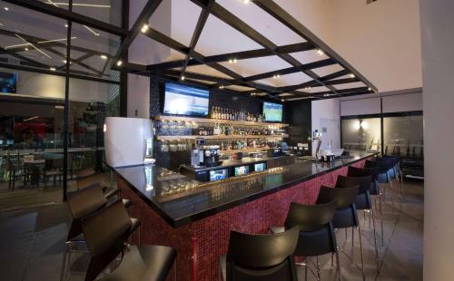 a bar in a restaurant with a bunch of chairs at Ramada Encore by Wyndham San Luis Potosi in San Luis Potosí