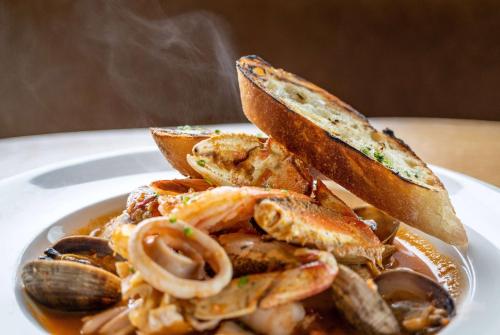 a plate of food with shrimp and bread and mushrooms at Pacifica Lighthouse Hotel Trademark Collection by Wyndham in Pacifica