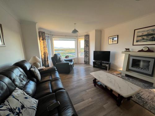 a living room with a leather couch and a fireplace at Lingeigh in Pollachar