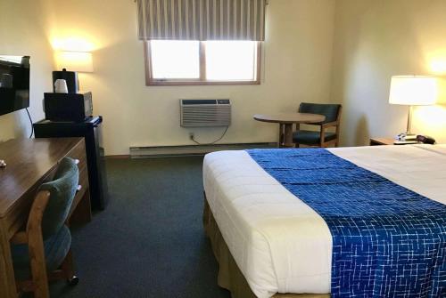 a hotel room with a bed and a desk and a window at Travelodge by Wyndham Three Forks in Three Forks