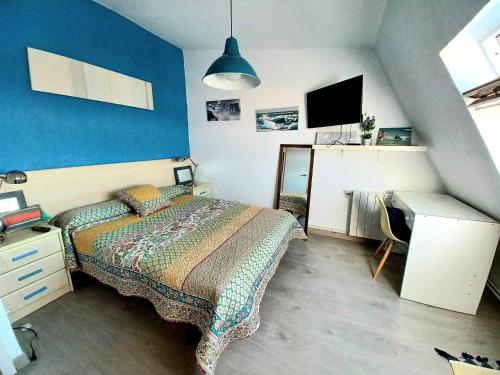 1 dormitorio con 1 cama con pared azul en Duplex con piscina muy cerca de la playa, en Santiuste
