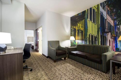 a hotel room with a couch and a painting on the wall at Clarion Pointe Charleston - West Ashley in Charleston