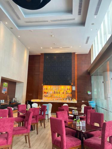 a restaurant with pink chairs and tables and a bar at Swiss-Belinn SKA Pekanbaru in Pekanbaru