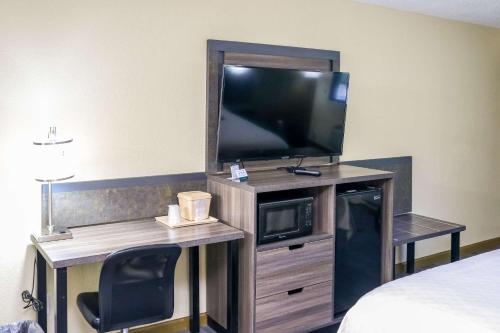 Habitación de hotel con TV y escritorio con silla. en Rodeway Inn, en Phenix City