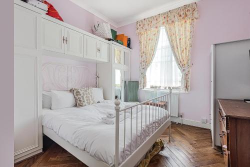 ein Schlafzimmer mit einem weißen Bett und einem Fenster in der Unterkunft Charming one bedroom flat near Maida Vale by UnderTheDoormat in London