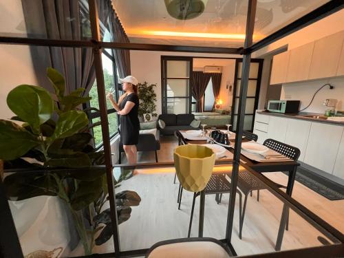 una mujer parada en una sala de estar mirando una sala de estar en Jesselton Quay Suite by Backyard en Kota Kinabalu