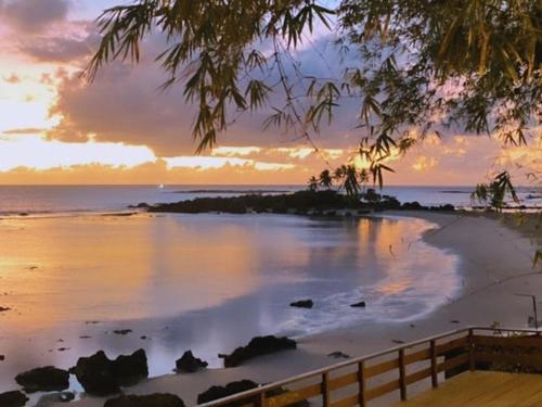 a sunset over a beach with a fence and the ocean at Axe Mainha Flats e Kitnet in Morro de São Paulo