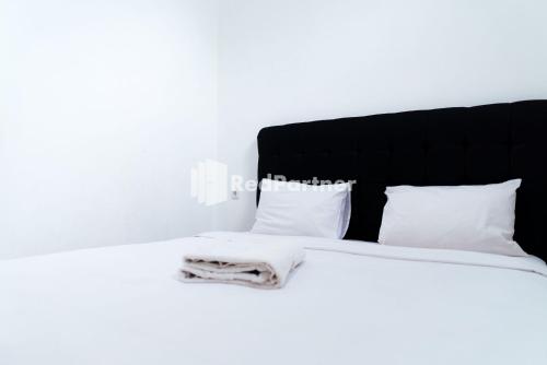 TanjungkarangにあるAksara Homestay Syariah Mitra RedDoorzの白いベッド(黒いヘッドボード、白い枕付)