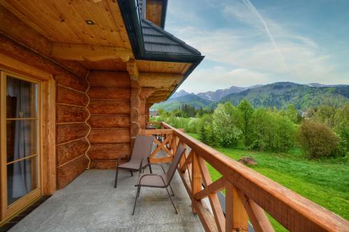 a porch of a log cabin with two chairs on it at Willa ANTONÓWKA in Kościelisko