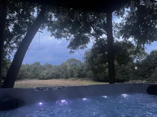 a hot tub with a view of a field and trees at Lynbrook Haybarn, Hot tub and outdoor kitchen, New Forest in Ringwood