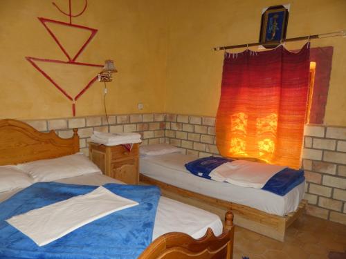 A bed or beds in a room at Les Pyramides Hotel Merzouga