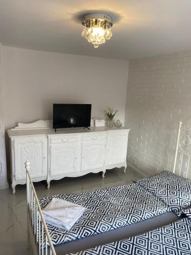 a bedroom with a white dresser with a television on it at White Apartment in Elblag