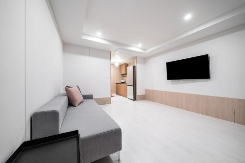 a living room with a couch and a flat screen tv at Geoje Mongdol Beach H Avenue Hotel in Geoje 