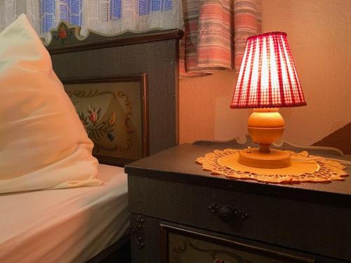 a red lamp on a table next to a bed at Gasthof-Pension Hochsteiner in Glödnitz