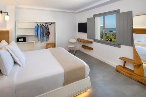 a bedroom with a white bed and a window at La Ponta Villas & Suites in Akrotiri